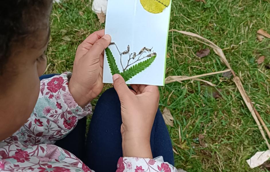 Kind erstellt eine Postkarte aus Naturmaterialien